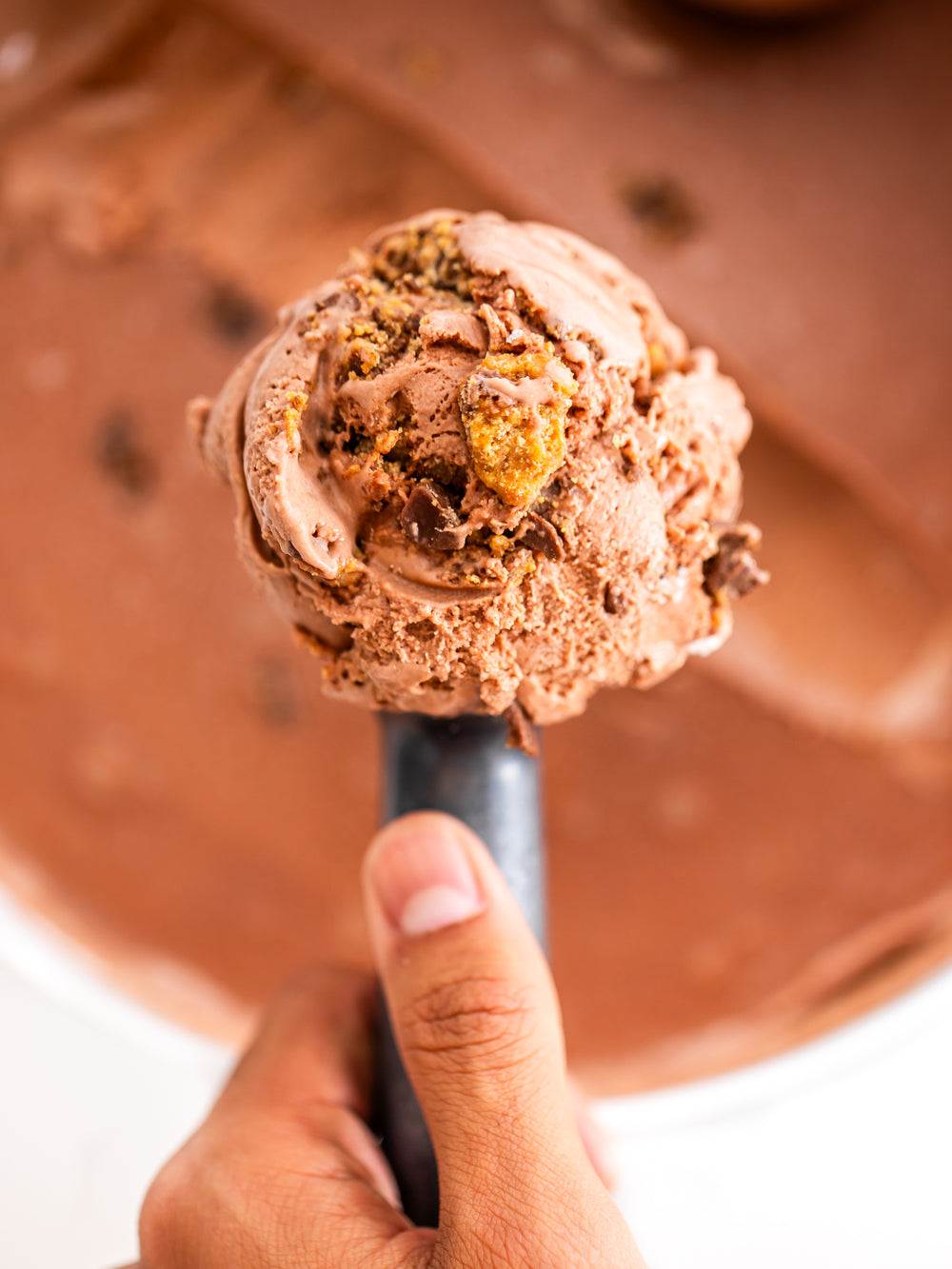Perfect PBC ice cream scoop on a spoon with a blurred chocolate background